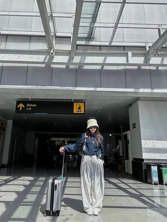 Airport look yang chic dari Fuji. Ia mengenakan atasan biru navy dengan siluet yang terstruktur dan celana panjang putih keabuan, beserta topi dan sepatunya yang serasi. [Foto: Instagram/fuji_an]
