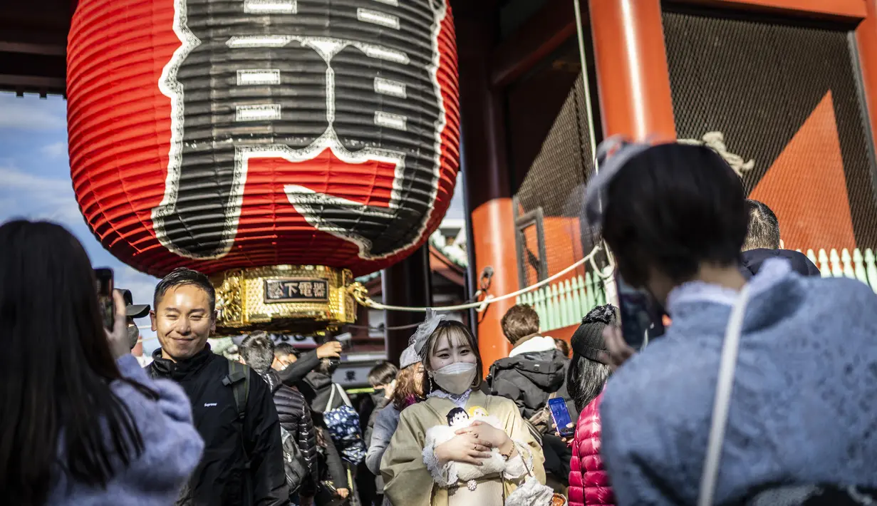 Orang-orang berfoto di kuil Sensoji menjelang liburan Tahun Baru di Tokyo pada 30 Desember 2022. Kuil Sensoji dikenal sebagai tempat wisata paling terkenal di Tokyo. (AFP/Yuichi Yamazaki)