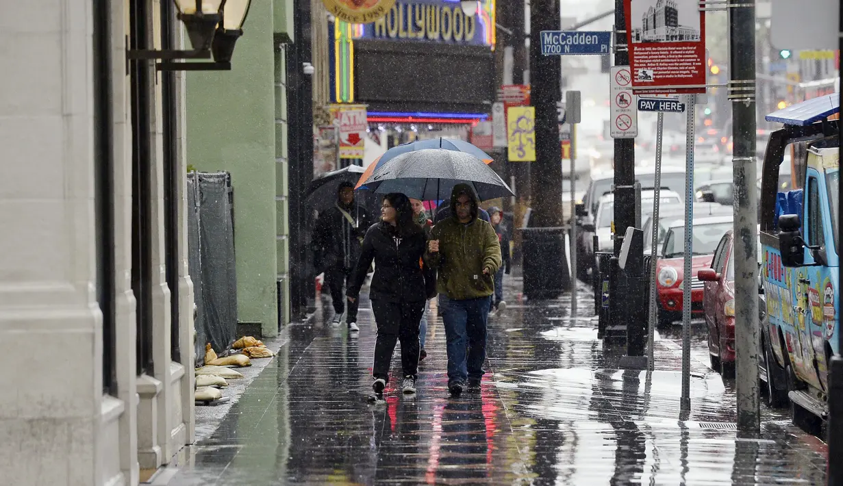 Wisatawan memakai payung sambil berjalan di trotoar Hollywood Walk of Fame di California, Rabu (6/1/2016). Badai El Nino melanda wilayah selatan California dengan membawa hujan deras ke kawasan yang sempat dilanda kekeringan. (REUTERS/Kevork Djansezian)