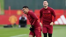 Pemain Manchester United, Casemiro dan Diogo Dalot, tampak semringah saat sesi latihan di Carrington Training Complex, Senin (23/10/2023). Mereka tampak bercanda dan tertawa bersama di sesi latihan. (AFP/Paul Ellis)