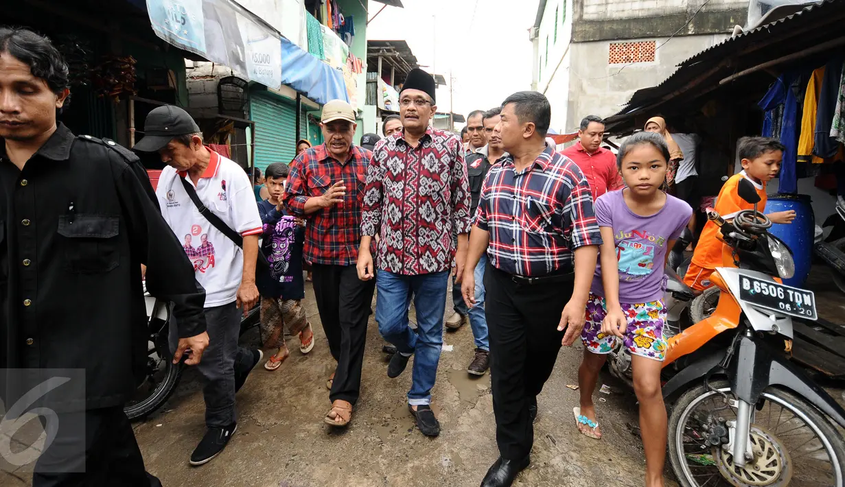 Cawagub petahana, Djarot Syaiful Hidayat (tengah) berjalan menyusuri salah satu gang saat sosialisasi di kawasan Pademangan VIII, Jakarta, Kamis (23/3). Selain sosialisasi, Djarot juga menyerap keluhan warga sekitar. (Liputan6.com/Helmi Fithriansyah)  