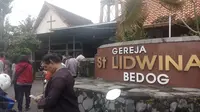 Petugas memasang garis polisi di pintu Gereja St Lidwina Bedog, Sleman, Yogyakarta, Minggu (11/2). (Liputan6.com/Yanuar H)