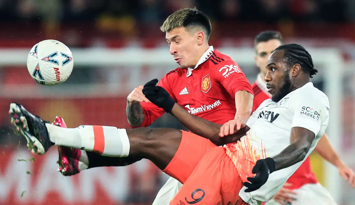 Pemain Manchester United, Lisandro Martinez (kiri) berebut bola dengan pemain West Ham, Michail Antonio pada laga putaran kelima Piala FA 2022/2023 yang berlangsung di Stadion Old Trafford, Manchester, Kamis (02/03/2023) WIB. MU berhasil menang comeback 3-1. (AFP/Lindsey Parnaby)
