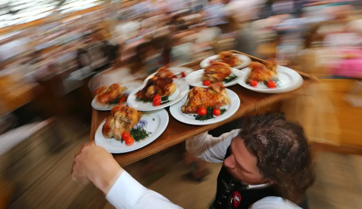 Seorang pelayan membawakan pesanan pengunjung saat Festival Bir Oktoberfest di Munich, Jerman, (19/9/2015). Oktoberfest di Jerman adalah festival bir terbesar di dunia yang akan berlangsung hingga 4 Oktober 2015. (AFP Photo / Josef Hildenbrand) 