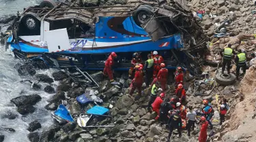 Petugas pemadam kebakaran mengevakuasi tubuh korban dari sebuah bus yang jatuh dari tebing setelah ditabrak oleh truk trailer, di Pasamayo, Peru, Selasa (3/1). Sedikitnya 35 orang tewas dalam insiden tersebut. (Vidal Tarky, Andina News Agency via AP)