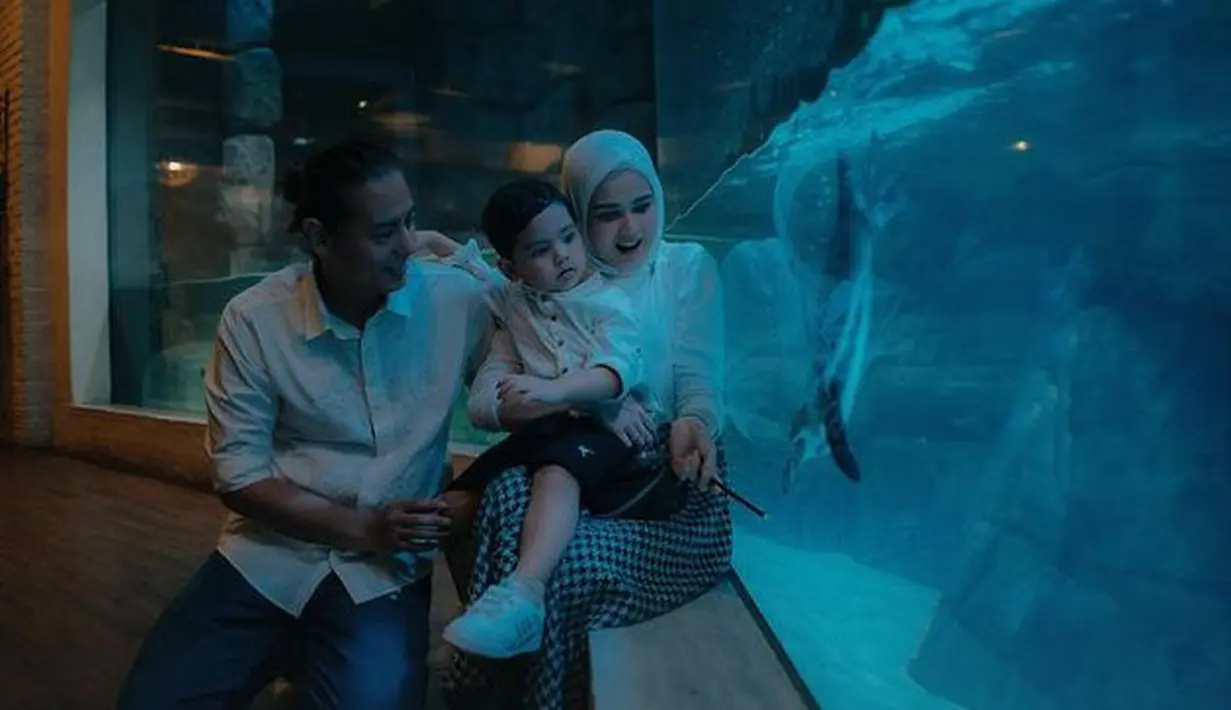 Roger Danuarta dan Cut Meyriska juga sempat menggendong Shaquille yang tumbuh besar. Lucu banget, mereka sedang menatap penguin yang tengah berenang di aquarium.(instagram.com/cutratumeyriska)