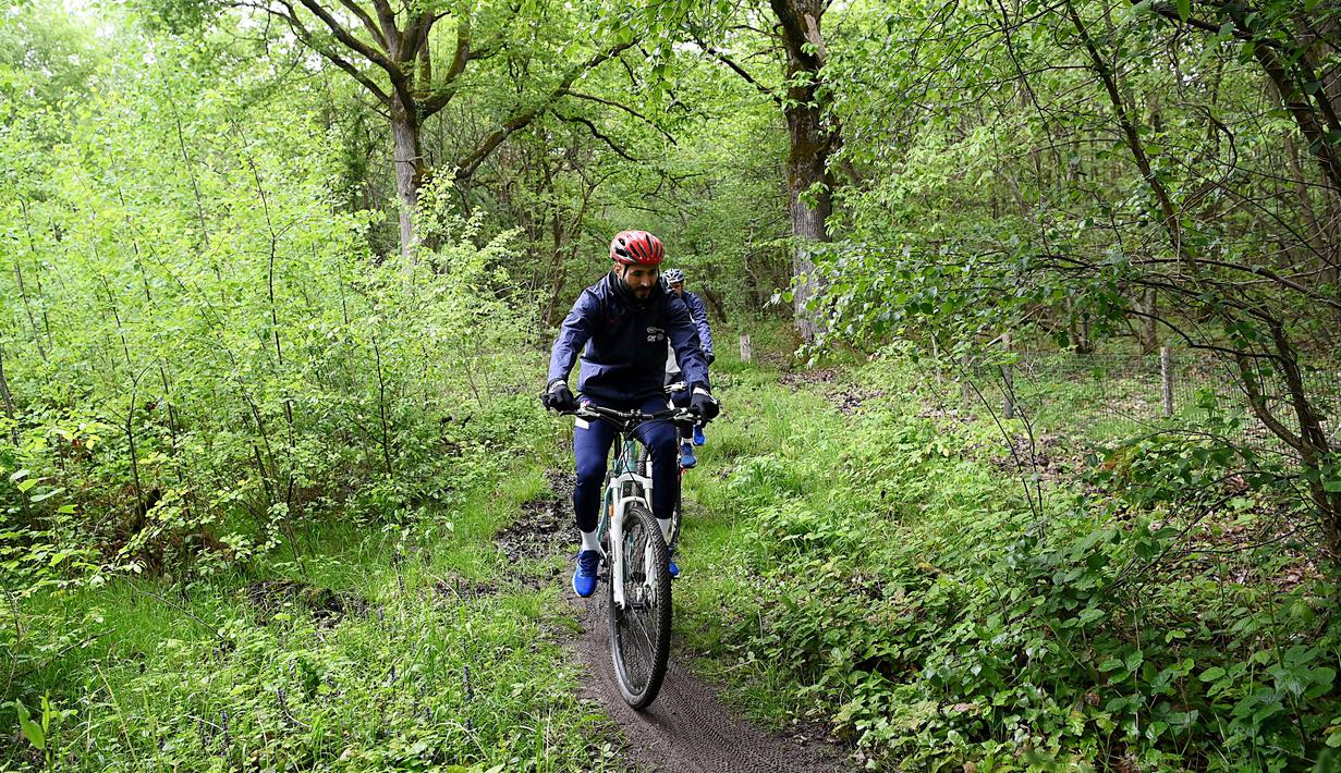 Karim Benzema mengendarai sepeda di Pusat latihan Timnas Prancis di Clairefontaine-en-Yvelines, Rabu (26/5/2021). Benzema kembali memperkuat Timnas Prancis setelah enam tahun absen. (AFP/Franck FIfe)