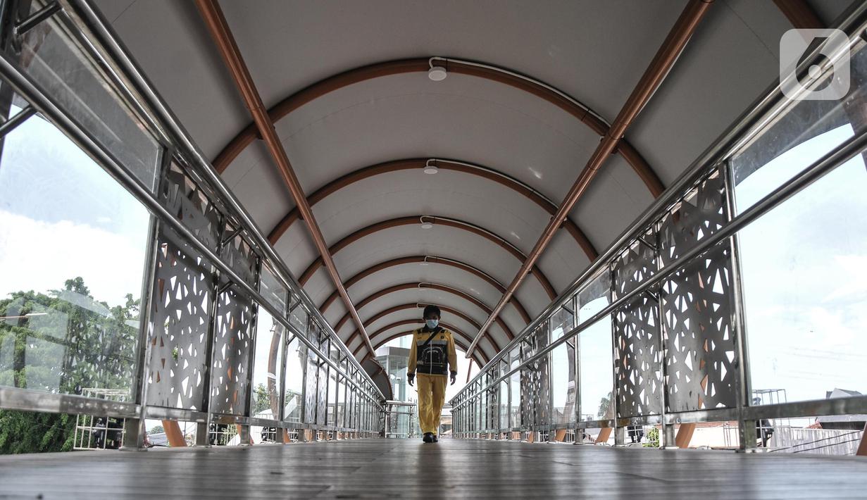 Pejalan kaki menggunakan fasilitas jembatan penyeberangan orang (JPO) di Jalan Kolonel Sugiono, Duren Sawit, Jakarta, Senin (7/2/2022). Tak hanya menonjolkan keindahan arsitekturnya, JPO ini juga ramah bagi penyandang disabilitas karena sudah dilengkapi dengan lift. (merdeka.com/Iqbal S Nugroho)