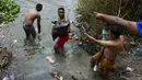 Dengan tenggat waktu larut malam yang semakin dekat, para migran di Meksiko melepaskan pakaian mereka sebelum menuruni jurang curam menuju Rio Grande, memegangi kantong plastik berisi pakaian. (AP Photo/Fernando Llano)