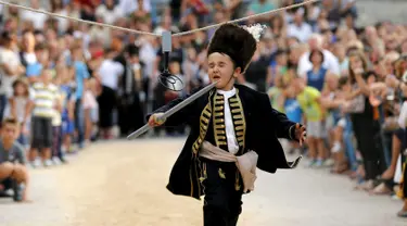 Seorang anak berlari memasukkan tombak kedalam lubang sasaran selama turnamen tradisional Alka di desa Vuckovici, Kroasia, Minggu (23/8/2015). Turnamen ini memperingati kemenangan Kroasia atas pemerintahan Turki Ottoman. (REUTERS/Antonio Bronic) 