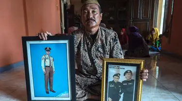 Edy Sujianto menunjukkan foto putranya Letnan Satu Muhammad Imam Adi yang bertugas dalam kapal selam KRI Nanggala 402 di Pasuruan, Jawa Timur, Minggu (25/4/2021). KRI Nanggala 402 hilang kontak di lepas pantai Bali pada 21 April dan kemudian dinyatakan tenggelam dengan 53 awak. (Juni Kriswanto/AFP)