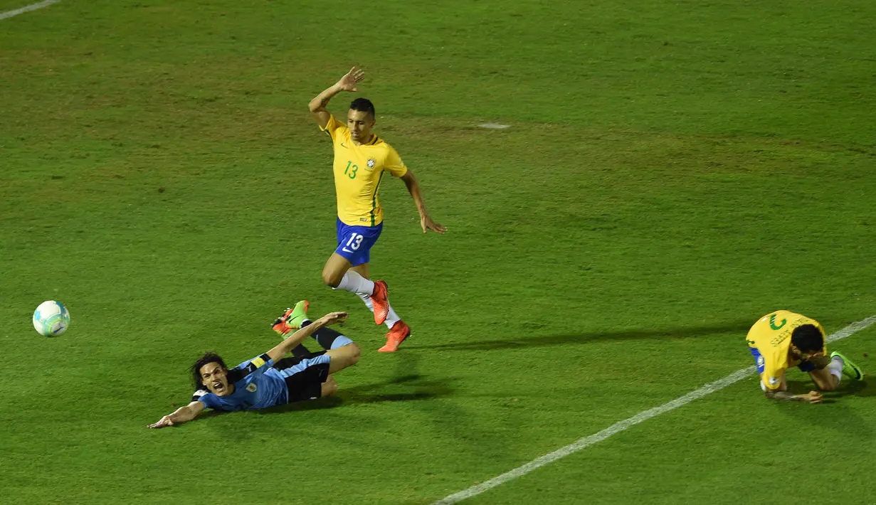 Striker Uruguay, Edinson Cavani, terjatuh saat perebutan bola dengan bek Brazil, Marquinhos. Kemenangan ini membuat Brasil semakin nyaman sebagai pemuncak klasemen sementara dengan koleksi 30 poin. (AFP/Pablo Porciuncula)