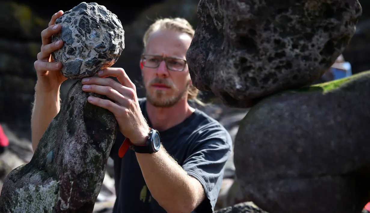 Philip Wachmann dari Austria berkompetisi dalam Kejuaraan Menumpuk Batu Eropa 2019 di Dunbar, Skotlandia, Minggu (21/4). Pemenang dalam kejuaraan tersebut akan terbang ke llano Earth Art Festival dan mengikuti World Stone Balancing Competition 2020. (Andy Buchanan / AFP)