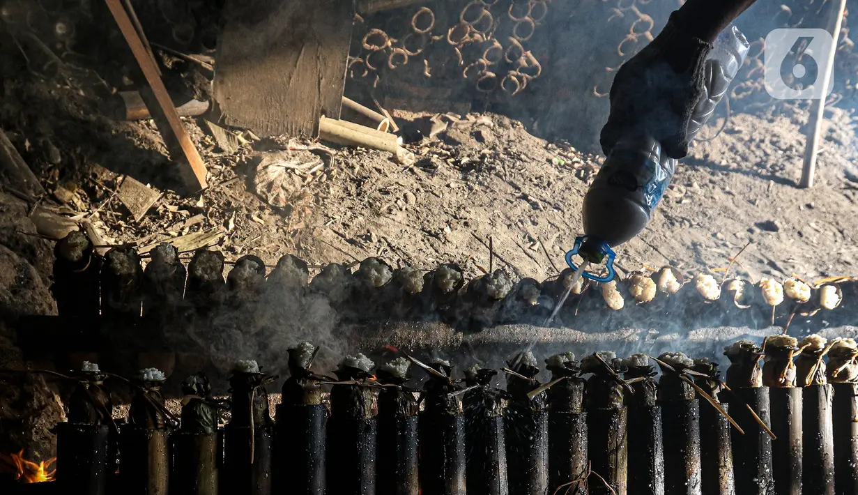 Pekerja melakukan pembakaran lemang bambu di Jalan Kramat Raya, Senen, Jakarta Pusat, Rabu (6/4/2022). Selama Ramadhan, pembuat lemang mampu memproduksi hingga 300 buah dalam sehari, meningkat hingga tiga kali lipat dari hari biasa. (Liputan6.com/Herman Zakharia)