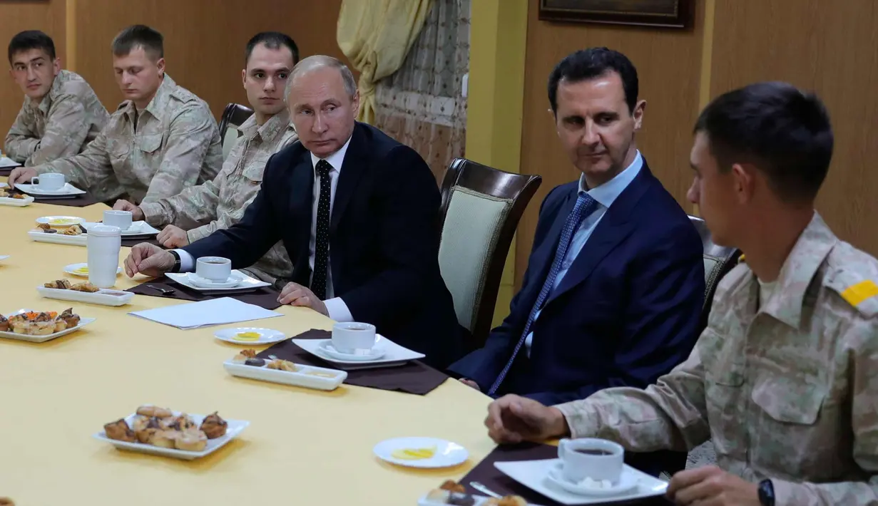 Presiden Rusia, Vladimir Putin dan Presiden Suriah, Bashar Assad saat melakukan pertemuan di pangkalan udara Hemeimeem di Suriah (11/12). Putin menyatakan akan menarik pasukan Rusia di Suriah. (Mikhail Klimentyev, Sputnik, Kremlin Pool Photo via AP)