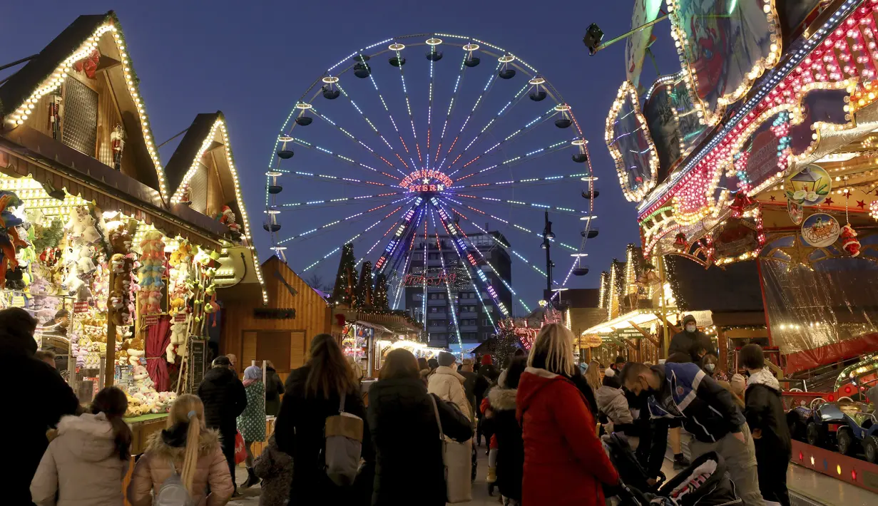 Pengunjung berjalan di pasar Natal, Rostock, Jerman, 22 November 2021. Menteri Kesehatan Jerman mengatakan bahwa peningkatan pesat kasus COVID-19 berarti kemungkinan semua orang di negara itu yang tidak divaksinasi akan tertular COVID-19 pada akhir musim dingin. (Bernd Woestneck/dpa via AP)