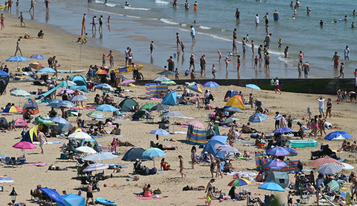 Para pengunjung berjemur menikmati sinar matahari di Pantai Bournemouth, Selatan Inggris pada Selasa 26 Mei 2026, saat kondisi gelombang panas menyebar ke sebagian wilayah tenggara Inggris dan London. (JUSTIN TALLIS/AFP)
