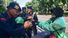 Pengemudi ojek daring/online (ojol) memberikan bunga mawar kepada salah satu personel kepolisian dari unsur Korps Brigade Mobil (Brimob) di sekitar kawasan Monumen Nasional, Jakarta, Selasa (2/9/2025). (merdeka.com/Arie Basuki)