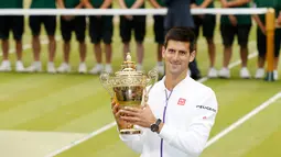 Petenis Serbia, Novak Djokovic menunjukkan trofi kemenangannya setelah mengalahkan petenis Swiss, Roger Federer di babak final tunggal putra Wimbledon 2015, London, Minggu (12/7). Ini adalah gelar Wimbledon ketiga bagi Djokovic.  (REUTERS/Stefan Wermuth)