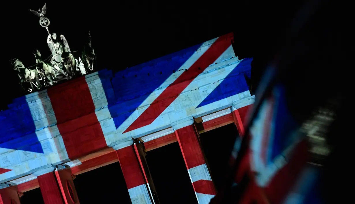 Warna bendera nasional Inggris menghiasi gerbang Brandenburg sebagai bentuk turut berduka cita atas teror London, di ibu kota Jerman, Berlin, Kamis (23/3). Aksi penyerangan di dekat parlemen Inggris itu menewaskan lima orang. (Tobias SCHWARZ/AFP)