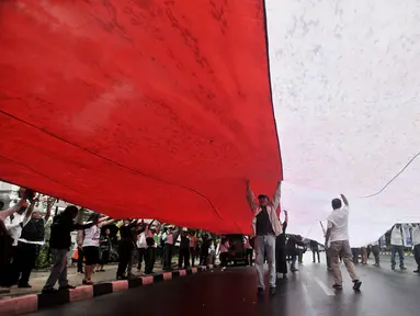 Massa GJI membentangkan bendera Merah Putih raksasa saat menggelar aksi menuntut Gubernur DKI Jakarta Anies Baswedan untuk mencabut izin penyelanggaraan Reuni 212 di depan Balai Kota, Jakarta, Kamis (29/11). (Merdeka.com/Iqbal S. Nugroho)
