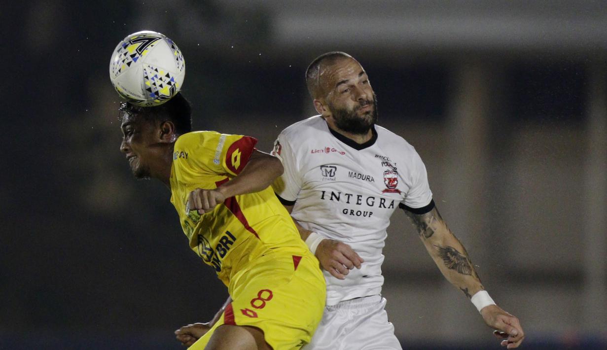 Gelandang Bhayangkara FC, M Hargianto, duel udara dengan striker Madura United, Aleksandar Rakic, pada laga Liga 1 2019 di Stadion Madya, Jakarta, Senin (5/8). (Bola.com/M iqbal Ichsan)