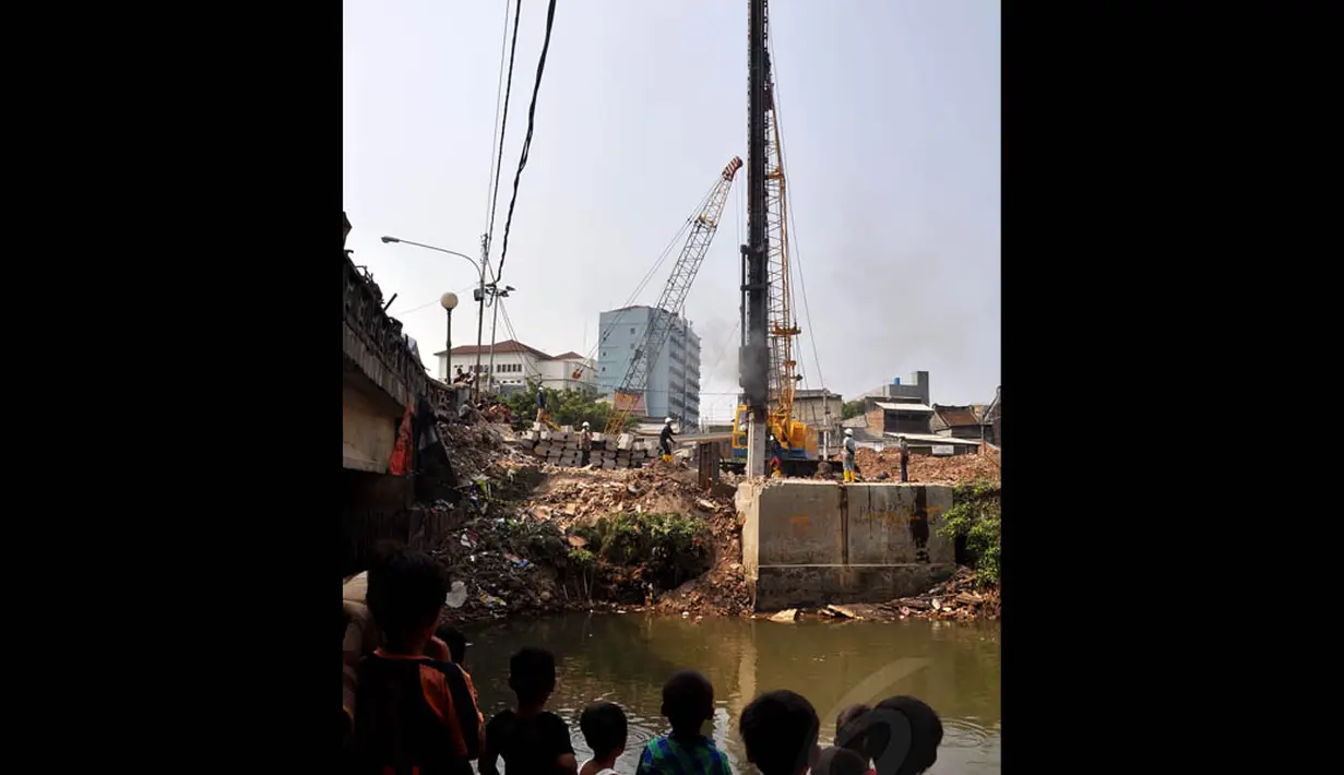 Sejumlah anak kecil tampak melihat pengerjaan pemasangan turap di Kali Ciliwung, Jakarta, Rabu (3/9/14). (Liputan6.com/Miftahul Hayat)