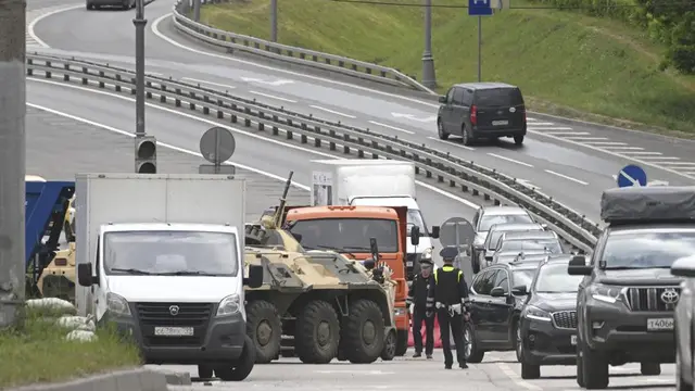 Seorang petugas APC (armoured personnel carrier) dan polisi berdiri di jalan raya di pintu masuk ke Moskow, Rusia, Sabtu, 24 Juni 2023. (Foto AP)