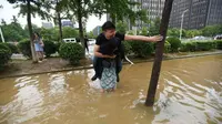 Gendong pacar seberangi banjir, perempuan ini jadi berita viral. Foto : CCTV News