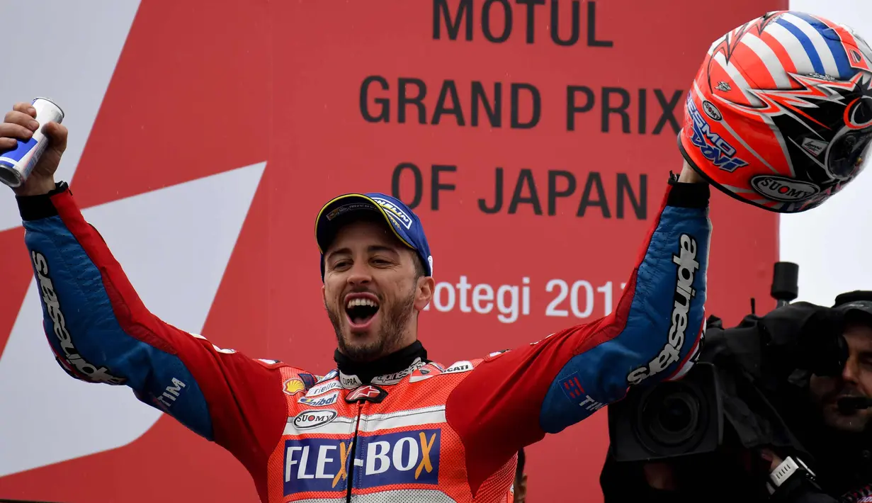 Pembalap Ducati, Andrea Dovizioso merayakan kemenangannya di atas podium usai memenangi MotoGP Jepang di sirkuit Motegi (15/10). Pembalap Ducati ini kini hanya 11 angka tertinggal dari Marc Marquez. (AFP Photo/Toshifumi Kitamura)