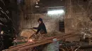 Seorang pekerja memotong besi di sebuah bengkel di Baghdad, Irak (20/2). Para pandai besi ini bekerja untuk membuat pasak tenda dan alat-alat pertanian. (AFP Photo/Ahmad Al-Rubaye)