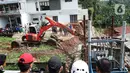 Petugas menggunakan alat berat berusaha merapikan posisi turap yang hancur di Jalan Damai, Ciganjur, Jakarta Selatan, Minggu (11/10/2020). Hujan yang deras sejak Sabtu (10/10/2020) sore mengakibatkan kawasan tersebut mengalami banjir sekaligus longsor. (Liputan6.com/Immanuel Antonius)