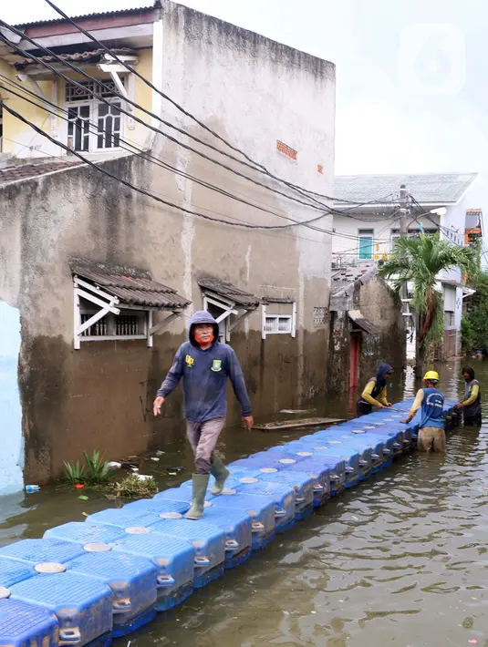 Petugas membuat jembatan apung saat banjir melanda Perumahan Periuk Damai, Tangerang, Banten, Selasa (23/2/2021). Adanya jembatan apung mempermudah warga saat melintasi banjir setinggi 2,5 meter di tempat tersebut. (Liputan6.com/Angga Yuniar)
