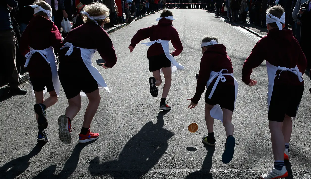Peserta menjatuhkan pancake saat lomba lari sembari membawa wajan berisi pancake di Olney, Buckinghamshire, Inggris, Selasa (28/2). Lomba yang digelar pada Hari Pancake atau Pancake Day ini diadakan satu hari menjelang Rabu Abu. (AP Photo/Alastair Grant)