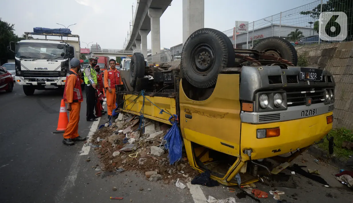 Petugas mengecek truk yang terbalik akibat salah satu ban belakang lepas di jalan tol Pondok Indah dekat pintu keluar Lebak Bulus, Jakarta, Jumat (29/5/2020). Dalam kecelakaan tersebut tidak ada korban jiwa namun membuat kendaraan yang melintas jalan tol tersendat. (merdeka.com/Dwi Narwoko)