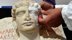 Peneliti memasangkan bagian wajah yang hilang dari sebuah patung yang berumur sekitar 2-3 abad di Roma, Kamis (16/2). Patung tersebut hancur akibat dari serangan ISIS. (AFP PHOTO / Alberto PIZZOLI)