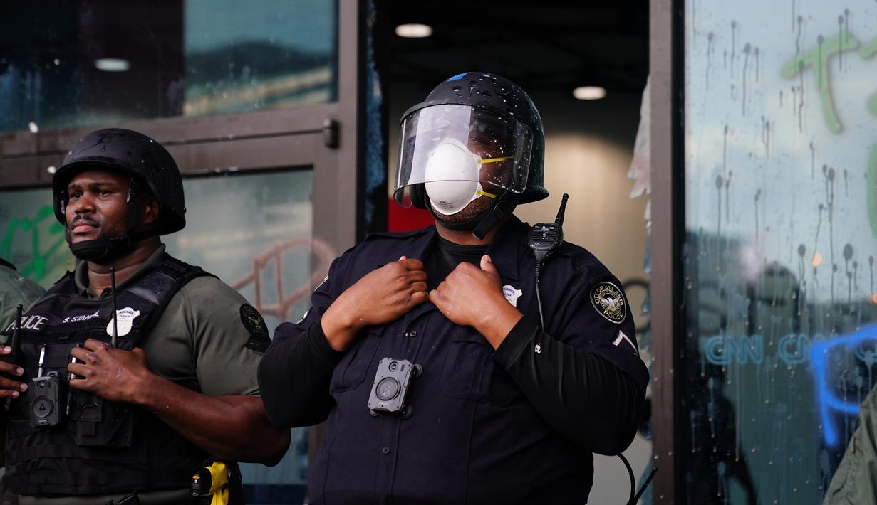 Aparat kepolisian melakukan penjagaan saat aksi protes di kantor pusat CNN di Atlanta, Georgia, Jumat (29/5/2020). Massa yang mengecam kematian George Floyd (46) oleh polisi melakukan vandalisme dan perusakan gedung CNN pusat. (Elijah Nouvelage/Getty Images/AFP)