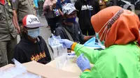 Petugas memberikan kantong kepada warga untuk menjalani tes GeNose C19 usai terjaring razia penggunaan masker di Kelurahan Sudimara Barat, Kota Tangerang, Kamis (27/5/2021). Tes tersebut untuk menekan penyebaran corona COVID-19 di wilayah tersebut. (Liputan6.com/Angga Yuniar)