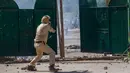 Polisi India bersiap menembakkan bom gas air mata ke arah mahasiswa Kashmir yang terlihat di gerbang kampus mereka di Srinagar, Kashmir yang dikuasai India, (23/5). (AP Photo/Dar Yasin) 