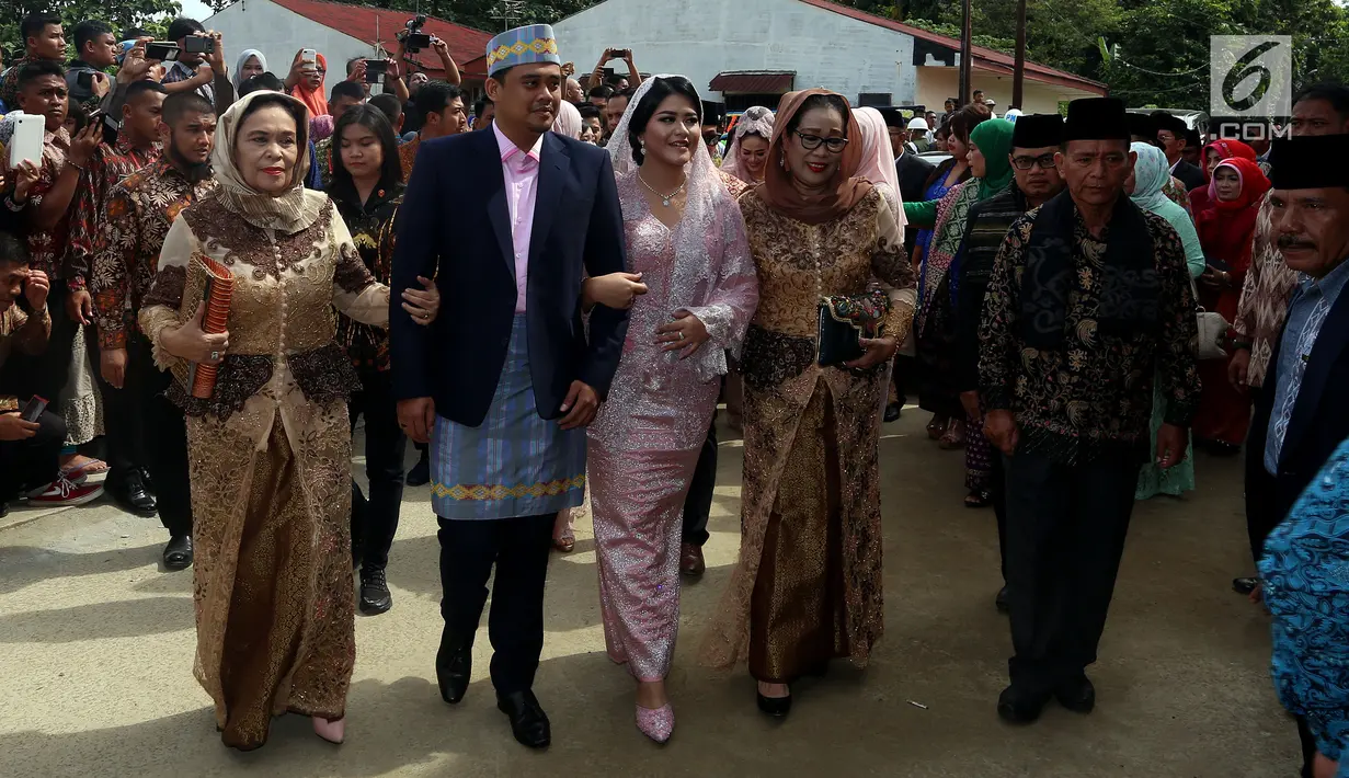 Kahiyang Ayu dan Bobby Nasution berjalan masuk ke lokasi upacara adat pemberian marga di rumah paman sang suami di Medan, Selasa (21/11). Kahiyang dan Bobby menebar senyum kepada para tamu undangan yang memenuhi lokasi. (Liputan6.com/Johan Tallo)