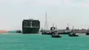 Kapal kargo Ever Given ditemani kapal tunda saat melaju di Terusan Suez, Mesir, Senin (29/3/2021). Ratusan kapal sedang menunggu untuk melewati kanal yang menghubungkan Mediterania ke Laut Merah. (Suez Canal Authority via AP)