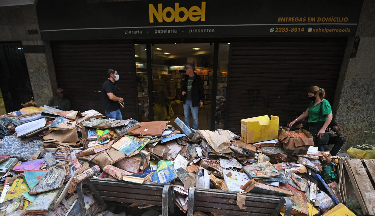 Ribuan buku rusak terlihat di jalan setelah hujan lebat membanjiri toko buku di Petropolis, Brasil, 19 Februari 2022. Sebanyak 136 jenazah telah diidentifikasi hingga kini, menurut pejabat pertahanan sipil, di kota wisata yang biasanya indah, sekitar 60 km utara Rio de Janeiro. (MAURO PIMENTEL/AFP)