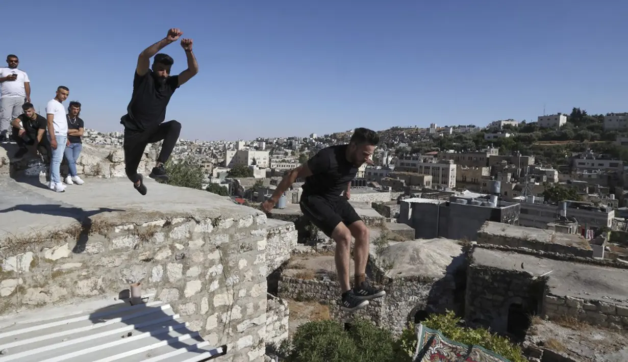 Pemuda Palestina Hammam Abu Sneineh (kiri) dan Abdallah al-Natsheh berlatih parkour di atas atap dan tangga rumah batu tradisional di Kota Hebron, Tepi Barat, Sabtu (5/6/2021). (HAZEM BADER/AFP)