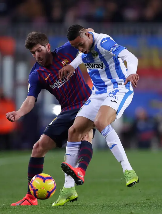 Pemain Barcelona, Sergio Roberto berebut bola dengan pemain Leaganes, Gerard Gumbau pada pertandingan pekan ke-20 La Liga Spanyol, di Camp Nou, Senin (21/1). Barcelona kian kokoh di puncak klasemen usai menang 3-1 atas Leganes. (AP/Manu Fernandez)