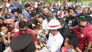 Suasana saat Presiden Joko Widodo atau Jokowi membagikan buku dan kain batik kepada warga sekitar Bandara Soetta, Tangerang, Banten, Kamis (21/6). Bagi-bagi buku tersebut merupakan rutinitas Jokowi usai blusukan. (Liputan6.com/Angga Yuniar)