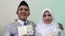 Komedian Caisar Aditya Putra dan Intan Sri Mardiani menunjukkan buku nikah usai melangsungkan ijab kabul pernikahan di kawasan Cimahpar, Bogor, Jawa Barat, Sabtu (30/6). (Liputan6.com/Herman Zakharia)