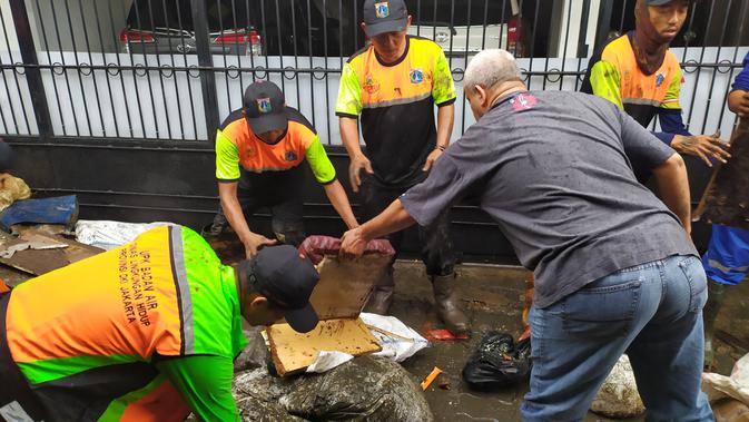 Sejumlah petugas membersihkan lumpur di kawasan Makasar, Jakarta Timur, usai terendam banjir. (Liputan6.com/Ika Defianti)