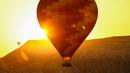 Para turis menaiki balon udara sambil menikmati matahari terbit di Kapadokia, Turki, Selasa (7/8). Cerobong Peri Kapadokia adalah lansekap batu vulkanik berbentuk kerucut yang menjulang tinggi ke langit. (AP Photo/Emrah Gurel)