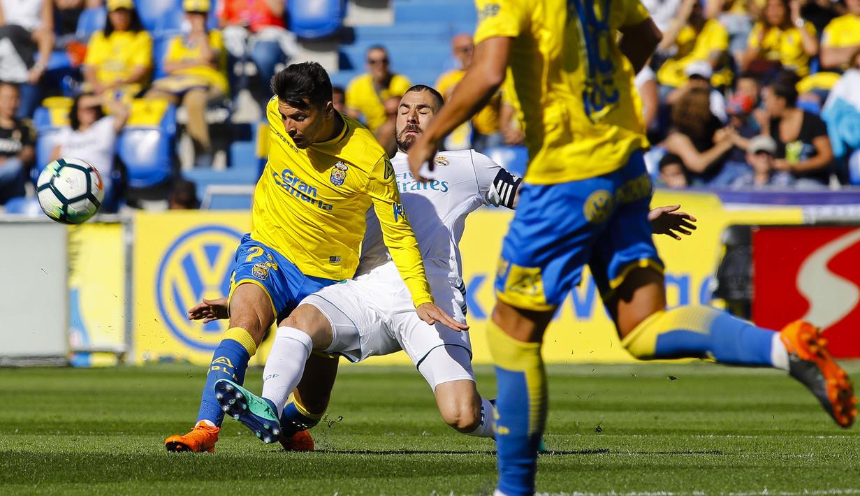 Pemain Real Madrid, Karim Benzema (tengah) berusaha merebut bola dari kaki pemain Las Palma, Ximo Navarro pada lanjutan La Liga Santander di Gran Canaria stadium, Canary island, (31/3/2018). Madrid menang 3-0. (AP/Lucas de Leon)