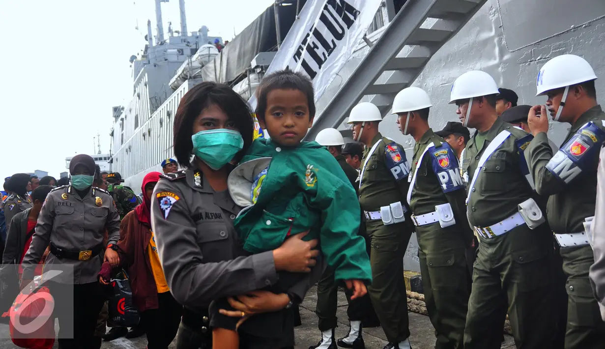 Petugas mengendong seorang anak di Pelabuhan Tanjung Emas, Semarang , Senin (25/1). Total ada 42 orang eks Gafatar yang sakit, terinci 28 dewasa dan 14 anak-anak. mengalami menderita dehidrasi, demam, dan  muntah.  (Liputan6.com/Gholib)